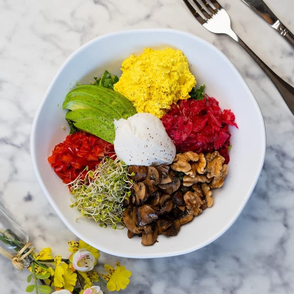 Colorful Green Table Cafe breakfast bowl with avocado, scrambled tofu, pickled cabbage, mushrooms, walnuts, and sprouts.