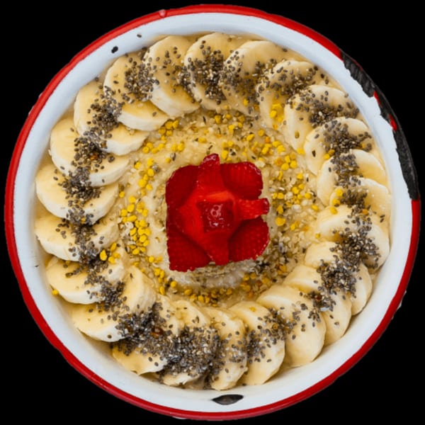 Overhead view of a Green Table Cafe oatmeal bowl with bananas, chia seeds, bee pollen, and a strawberry.