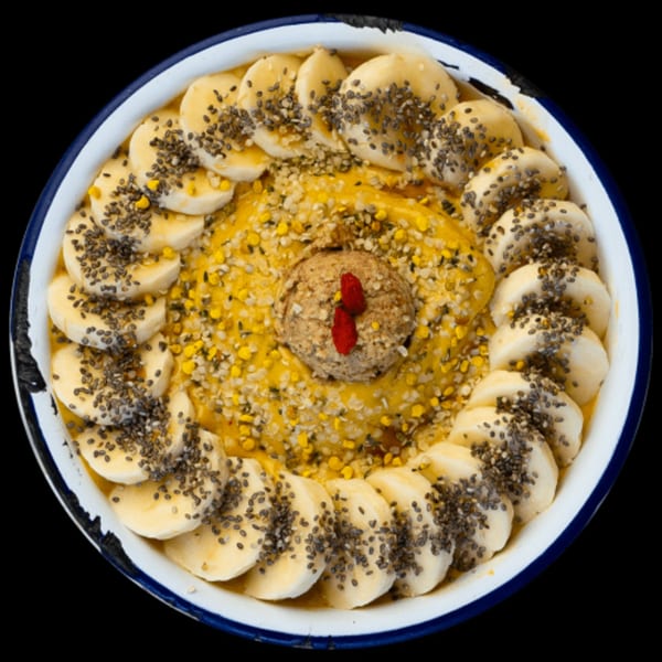 Overhead view of a Green Table Cafe smoothie bowl with bananas, chia seeds, and bee pollen.