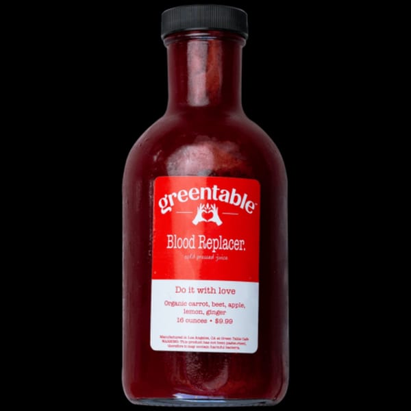 Green Table Cafe's "Blood Replacer" cold-pressed juice bottle with a red label and black cap.