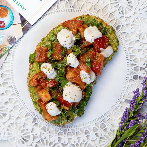 Green Table Cafe's avocado toast with tomatoes, mozzarella, and herbs on a white lace placemat.