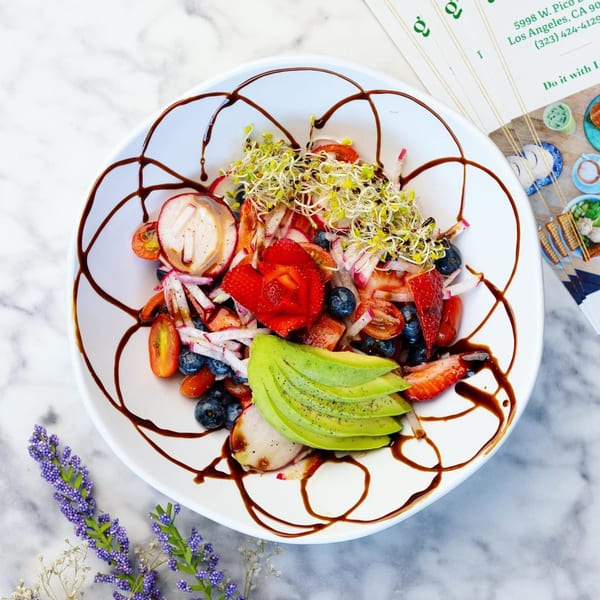 Green Table Cafe's colorful salad with strawberries, blueberries, avocado, radishes, and sprouts, drizzled with balsamic glaze.