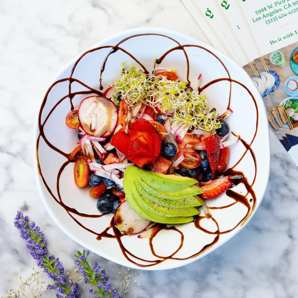Green Table Cafe's colorful salad with strawberries, blueberries, avocado, radishes, and sprouts, drizzled with balsamic glaze.