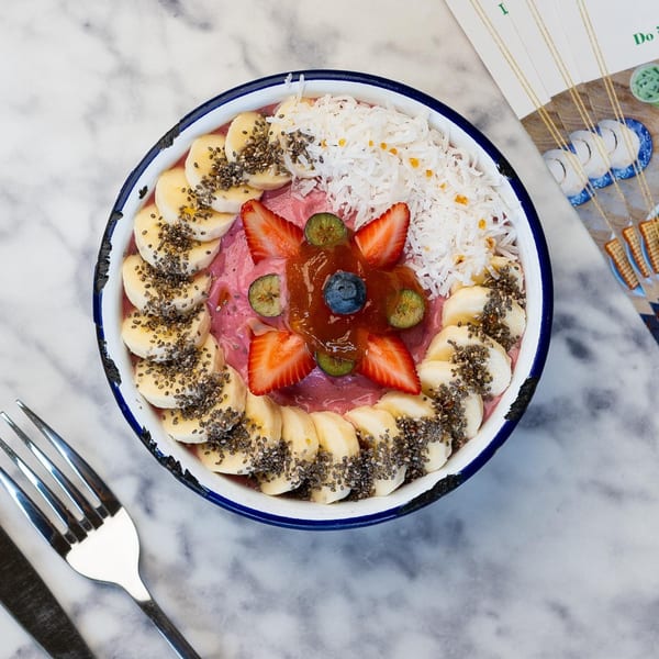 Overhead view of a Green Table Cafe smoothie bowl with bananas, strawberries, coconut, and chia seeds.
