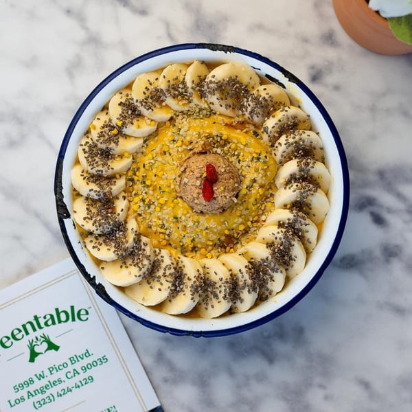 Overhead view of a Green Table Cafe smoothie bowl with bananas, chia seeds, and bee pollen.