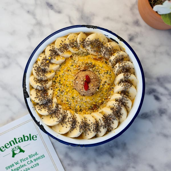 Overhead view of a Green Table Cafe smoothie bowl with bananas, chia seeds, and goji berries.